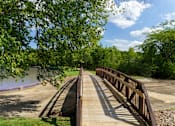 Thumbnail 65 of 112 - A bridge over a river with trees on the left at The Residences at Tesson Ridge Apartments, Saint Louis, MO, 63128