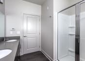 Thumbnail 44 of 54 - a bathroom with a shower and a sink and a mirror