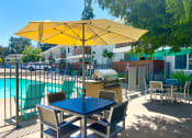 Thumbnail 29 of 31 - a patio with a table and chairs with an umbrella and a swimming pool