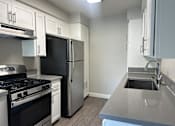 Thumbnail 4 of 25 - A kitchen with a black stove top oven and a black refrigerator.