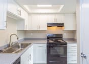 Thumbnail 2 of 17 - a kitchen with white cabinets and black appliances