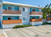 Thumbnail 7 of 31 - a blue and white apartment building with a parking lot in front of it