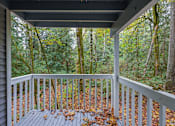 Thumbnail 3 of 31 - A wooden deck with a railing and leaves on the ground.