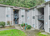 Thumbnail 21 of 31 - A grey apartment building with a small garden in front.
