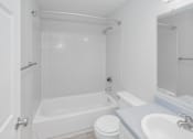 Thumbnail 30 of 31 - A white bathroom with a toilet, sink, and bathtub.