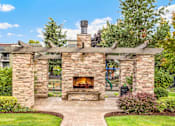 Thumbnail 20 of 27 - A stone fireplace is the centerpiece of a landscaped yard.