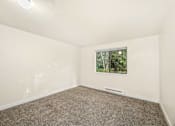 Thumbnail 16 of 27 - A room with a carpeted floor and a window showing trees outside.