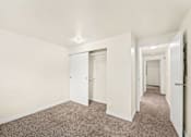 Thumbnail 17 of 27 - A long hallway with carpeted floors and white walls.