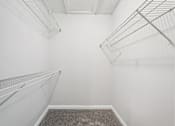Thumbnail 25 of 40 - Empty walk-in closet with white walls and shelving.