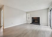 Thumbnail 24 of 40 - A large empty room with a fireplace and wood flooring.
