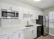 Thumbnail 28 of 40 - A kitchen with white cabinets and a black refrigerator.