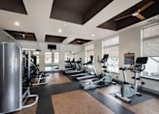 Thumbnail 5 of 33 - A gym with treadmills, elliptical machines, and a weight machine.