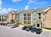 Thumbnail 23 of 24 - A parking lot in front of a multi-story apartment building.