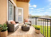 Thumbnail 9 of 24 - A balcony with a chair, couch, and table with a view of the street.