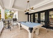 Thumbnail 7 of 40 - A pool table is in the middle of a room with a bar and chairs.