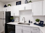 Thumbnail 13 of 40 - A kitchen with white cabinets and a black fridge.