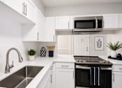 Thumbnail 14 of 40 - A modern kitchen with white cabinets and a black oven.