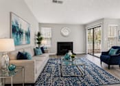 Thumbnail 21 of 40 - 1-Bedroom Apartments in Sandy Springs, GA - Veridian at Sandy Springs - Living Room With A Beige Sofa, Blue Accent Chair, Fireplace, Glass Coffee Table, Large Area Rug, And Sliding Glass Door.