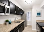 Thumbnail 20 of 40 - One-Bedroom Apartments in Sandy Springs, GA - Veridian at Sandy Springs - Kitchen With Black Cabinets, Beige Countertops, Stainless Steel Appliances, A Single Basin Sink, And Light Wood Flooring.