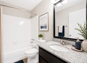 Thumbnail 23 of 40 - A bathroom with a white toilet, a sink, and a mirror.