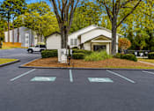 Thumbnail 37 of 40 - A parking lot with a white car and a white building in the background.