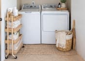 Thumbnail 17 of 25 - A laundry room with a washer and dryer, a basket on the floor, and a rack with towels.