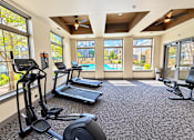 Thumbnail 7 of 30 - A spacious gym with treadmills, elliptical machines, and a stationary bike.