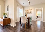 Thumbnail 12 of 30 - A dining room with a wooden table and chairs.