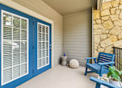 Thumbnail 27 of 28 - A blue chair sits on a porch next to a potted plant.