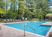 Thumbnail 10 of 40 - A large swimming pool surrounded by trees and chairs.