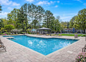 Thumbnail 8 of 40 - Sandy Springs, GA, Apartments Near Northside Hospital Atlanta - Veridian at Sandy Springs - Swimming Pool With Lounge Chairs, Paved Sundeck, Covered Gazebo, Landscaped Greenery, and Tall Trees.