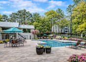 Thumbnail 9 of 40 - A pool surrounded by chairs and flowers with a house in the background.