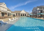 Thumbnail 23 of 27 - a swimming pool with chairs and umbrellas in front of a building with apartments