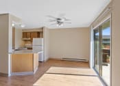 Thumbnail 1 of 7 - an empty living room with a kitchen and a ceiling fan