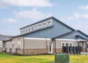 Thumbnail 1 of 19 - the front of the clubhouse with a blue and gray roof and a green lawn