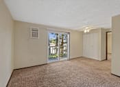 Thumbnail 2 of 5 - A room with a carpeted floor and a sliding glass door leading to a balcony.