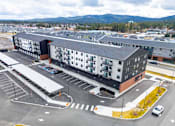 Thumbnail 4 of 18 - A large building with a parking lot in front of it.