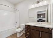 Thumbnail 7 of 18 - A white toilet sits in a bathroom next to a sink and a mirror.