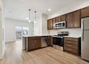 Thumbnail 13 of 18 - A modern kitchen with wooden cabinets and stainless steel appliances.