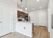 Thumbnail 15 of 18 - A kitchen with white cabinets and a white island.