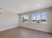 Thumbnail 4 of 13 - an empty bedroom with large windows and wood flooring