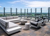 Thumbnail 7 of 24 - A set of outdoor furniture is arranged on a patio with a cityscape view in the background.