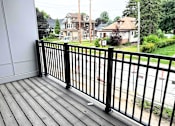 Thumbnail 10 of 34 - A black metal railing on a wooden deck overlooks a residential street.