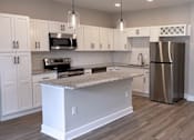 Thumbnail 2 of 34 - A modern kitchen with a central island and stainless steel appliances.
