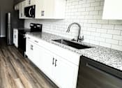 Thumbnail 4 of 34 - A kitchen with white cabinets and a black dishwasher.