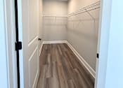 Thumbnail 9 of 34 - A hallway with white walls and wood flooring.