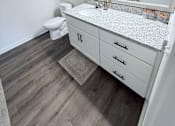 Thumbnail 53 of 61 - A bathroom with a white toilet and a counter with a mirror above it.