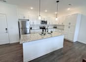 Thumbnail 13 of 61 - A kitchen with white cabinets and a granite countertop.