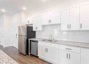 Thumbnail 14 of 61 - A kitchen with white cabinets and a black fridge.