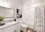 Thumbnail 29 of 34 - A bathroom with a white toilet, sink, and shower curtain.
